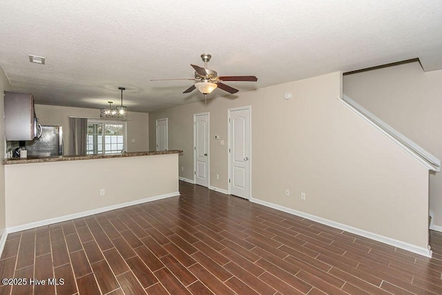 unfurnished living room with ceiling fan with notable chandelier and a textured ceiling