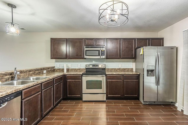 kitchen featuring appliances with stainless steel finishes, sink, hanging light fixtures, dark brown cabinetry, and a textured ceiling