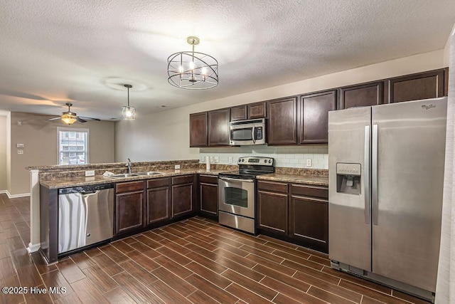 kitchen featuring dark brown cabinetry, sink, decorative light fixtures, stainless steel appliances, and decorative backsplash