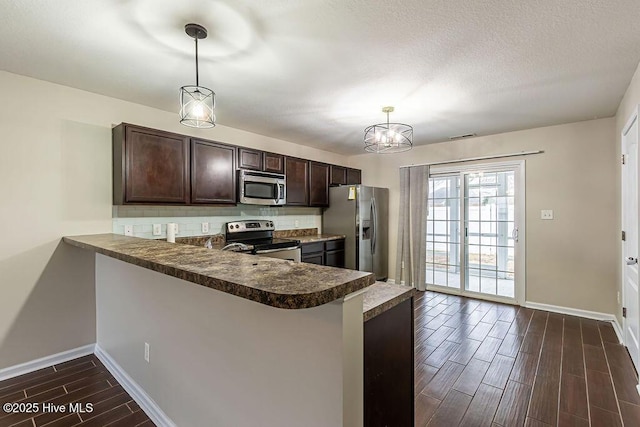 kitchen with a breakfast bar area, appliances with stainless steel finishes, dark brown cabinetry, decorative light fixtures, and kitchen peninsula