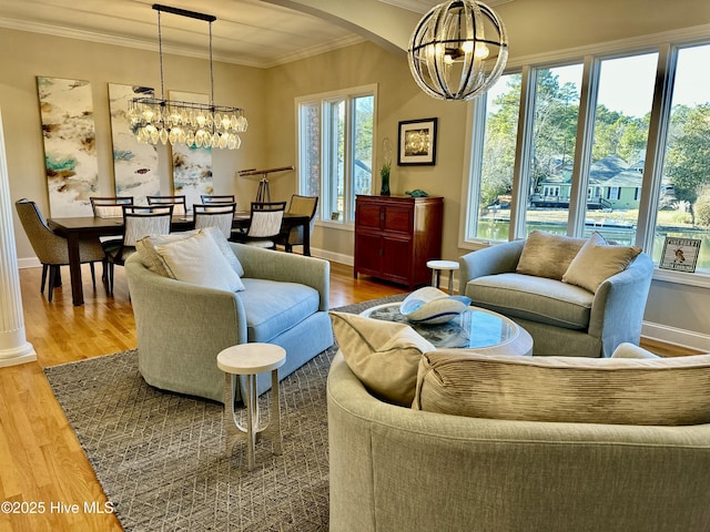 living room featuring an inviting chandelier, ornamental molding, and hardwood / wood-style flooring