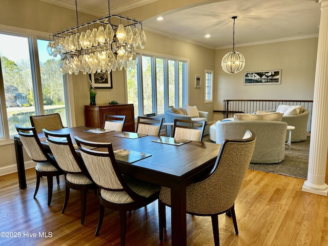 dining area featuring ornate columns, a healthy amount of sunlight, light hardwood / wood-style flooring, and crown molding