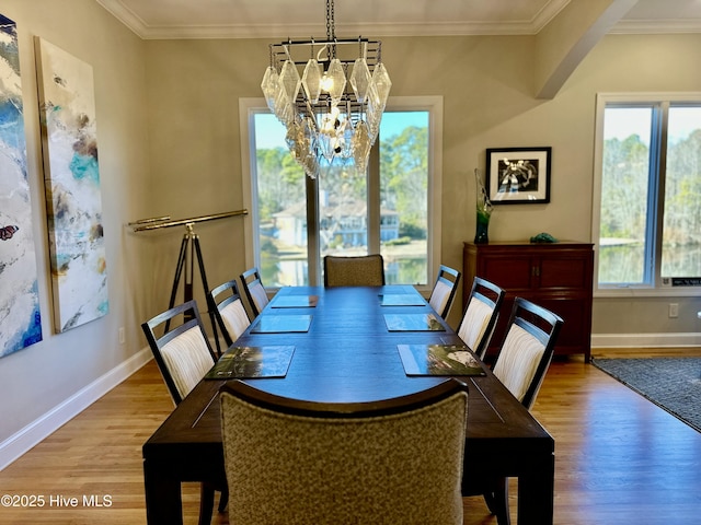 dining area with a healthy amount of sunlight, light wood-type flooring, and an inviting chandelier