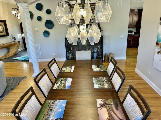 dining space with light wood-type flooring and ornate columns