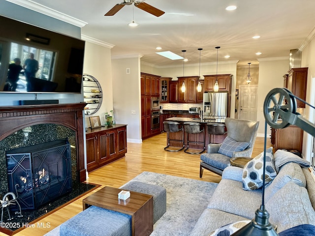 living room with light hardwood / wood-style floors, ceiling fan, a fireplace, ornamental molding, and sink