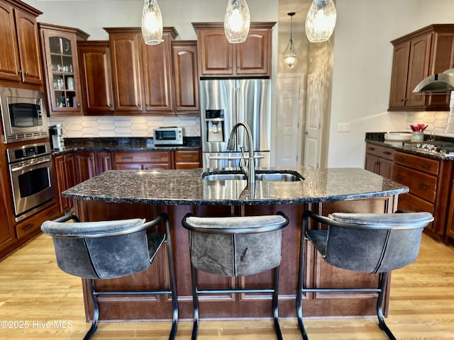 kitchen featuring tasteful backsplash, sink, appliances with stainless steel finishes, an island with sink, and a breakfast bar area