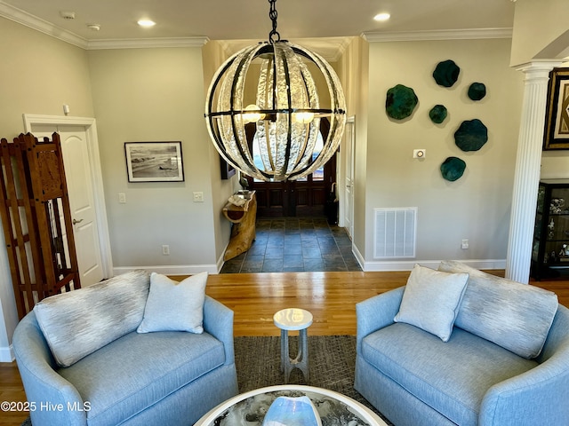 living room featuring dark hardwood / wood-style flooring, an inviting chandelier, ornamental molding, and ornate columns