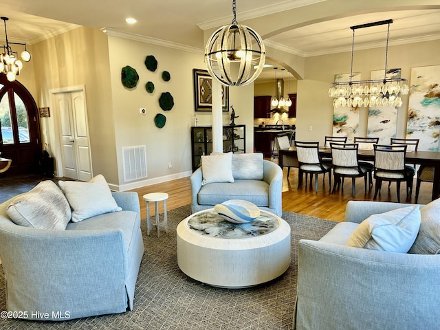 living room with an inviting chandelier, crown molding, and wood-type flooring