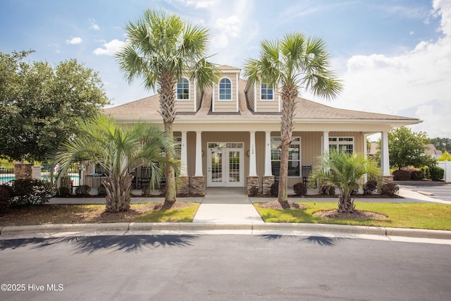 7195 Bonaventure St SW Apt 104, Ocean Isle Beach, NC 28469 - view of front facade with french doors, a porch, roof with shingles, and stone siding