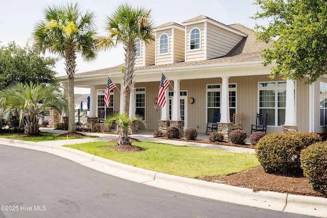7195 Bonaventure St SW Apt 104, Ocean Isle Beach, NC 28469 - view of front facade featuring a porch, roof with shingles, and a front yard