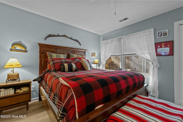 bedroom with light wood-type flooring and a textured ceiling