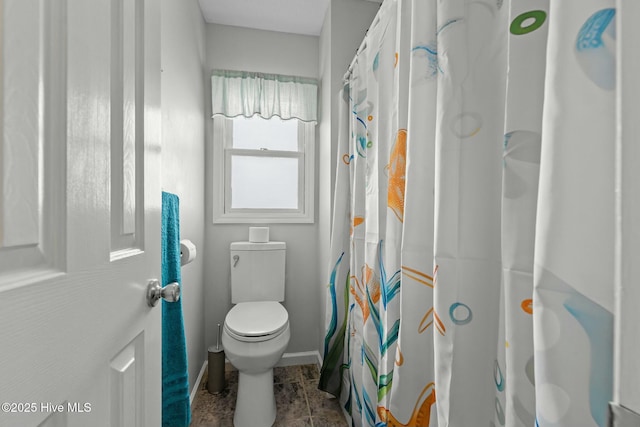 bathroom featuring toilet and curtained shower