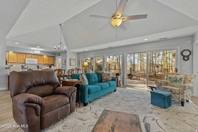 living room featuring lofted ceiling, ceiling fan with notable chandelier, a textured ceiling, and light hardwood / wood-style floors