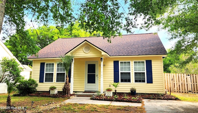 bungalow-style house featuring fence and roof with shingles