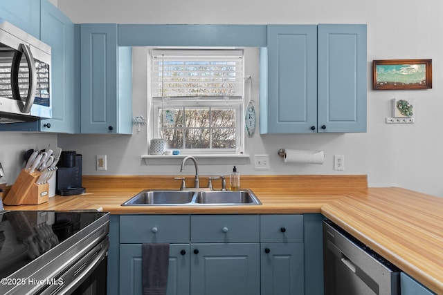 kitchen with blue cabinetry, stainless steel appliances, and sink