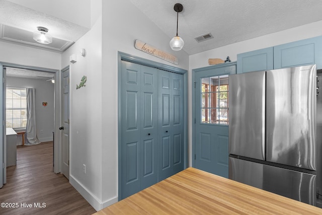 kitchen featuring decorative light fixtures, dark wood-type flooring, stainless steel refrigerator, and a textured ceiling