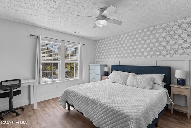 bedroom with wood-type flooring, ceiling fan, and a textured ceiling