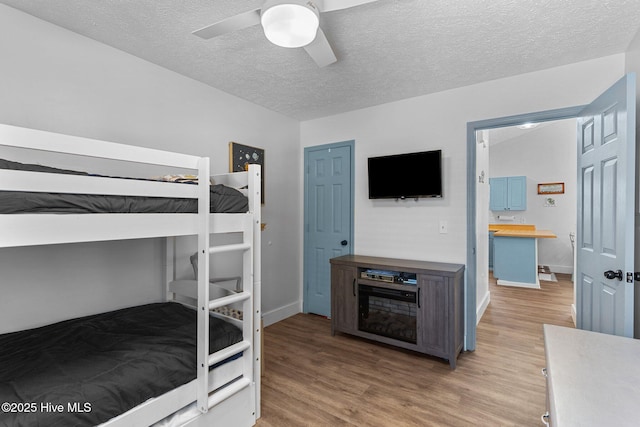 bedroom with ceiling fan, a textured ceiling, and light hardwood / wood-style flooring