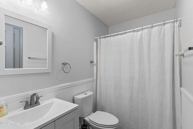 bathroom featuring vanity, toilet, a shower with shower curtain, and a textured ceiling