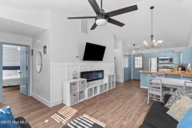 living room featuring sink, ceiling fan with notable chandelier, light hardwood / wood-style flooring, and high vaulted ceiling