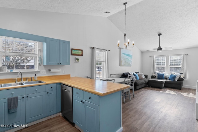 kitchen with dark wood-type flooring, lofted ceiling, sink, dishwasher, and kitchen peninsula