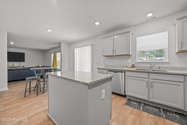 kitchen featuring visible vents, a sink, light wood-style floors, dishwasher, and a center island