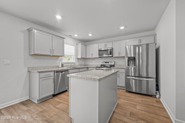 kitchen with light stone counters, light wood-style flooring, and appliances with stainless steel finishes