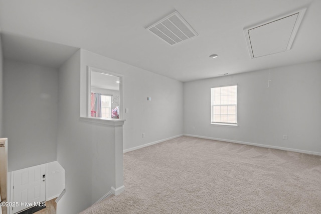 carpeted spare room with visible vents, plenty of natural light, attic access, and baseboards