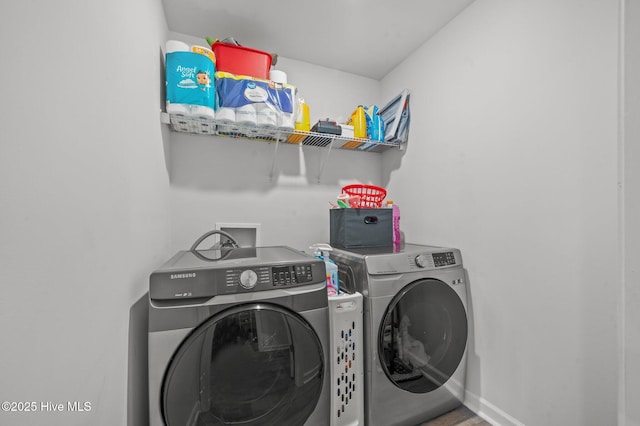 washroom with baseboards, independent washer and dryer, and laundry area