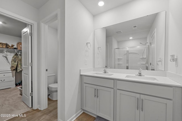 bathroom with toilet, hardwood / wood-style floors, vanity, and a shower with shower door