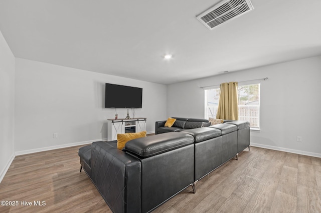 living room with visible vents, baseboards, and wood finished floors