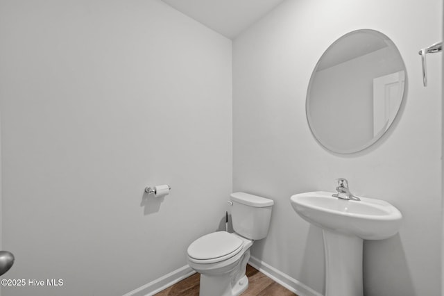 bathroom featuring toilet, baseboards, and wood finished floors