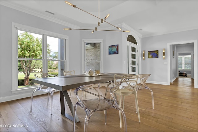 dining space with crown molding, an inviting chandelier, visible vents, and light wood-style floors