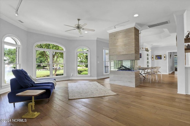 living room with crown molding, a multi sided fireplace, and wood-type flooring