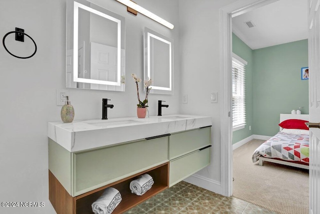 bathroom with baseboards, double vanity, a sink, and visible vents