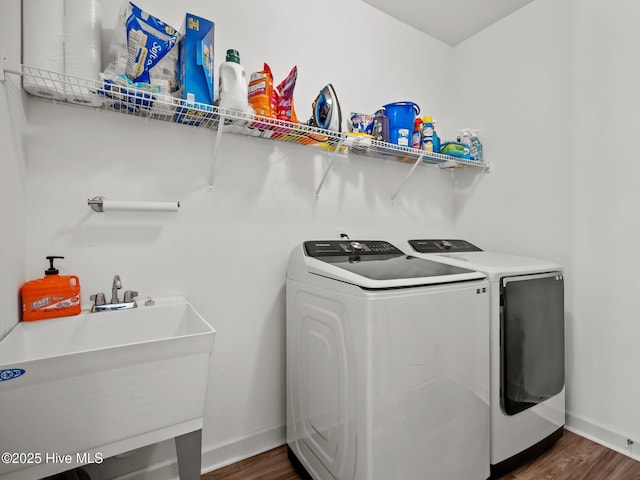 clothes washing area with washer and dryer, sink, and dark wood-type flooring