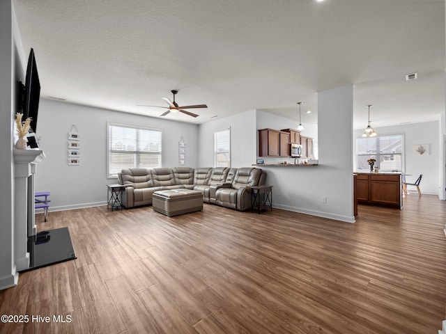 living room with hardwood / wood-style flooring, a textured ceiling, and ceiling fan