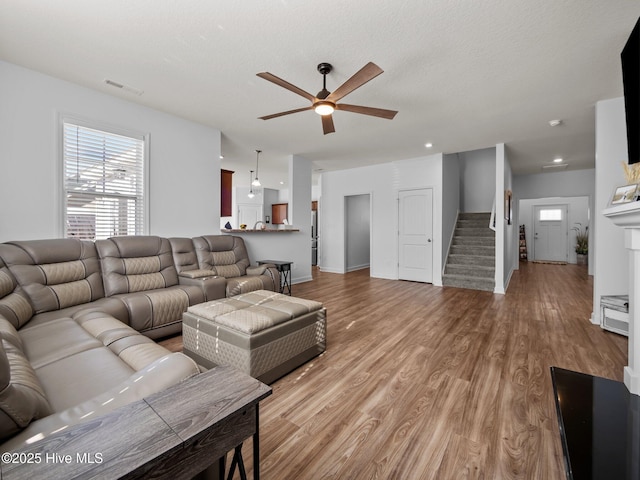 living room with ceiling fan, a textured ceiling, and light hardwood / wood-style floors