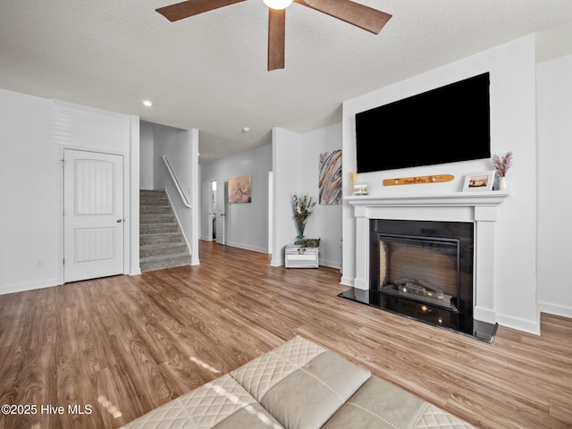 unfurnished living room with a textured ceiling, ceiling fan, and light hardwood / wood-style flooring