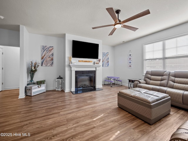 living room featuring hardwood / wood-style flooring, a textured ceiling, and ceiling fan