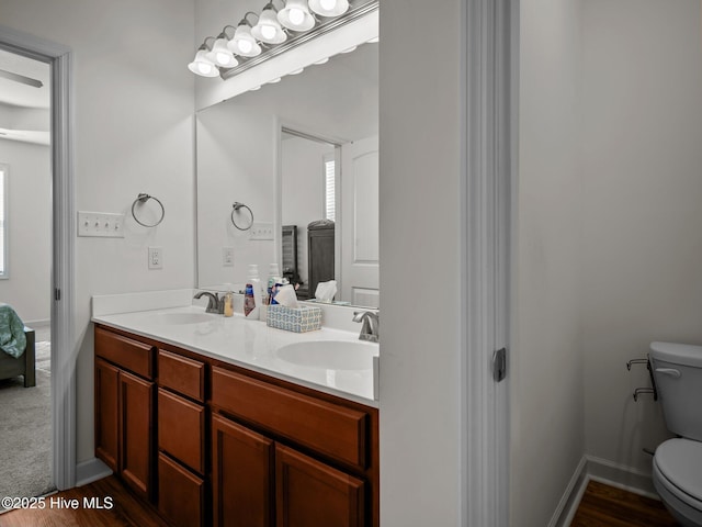 bathroom with vanity, wood-type flooring, a healthy amount of sunlight, and toilet