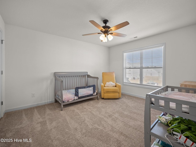 bedroom with light carpet, a nursery area, and ceiling fan