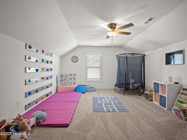 game room with ceiling fan, lofted ceiling, light colored carpet, and a textured ceiling