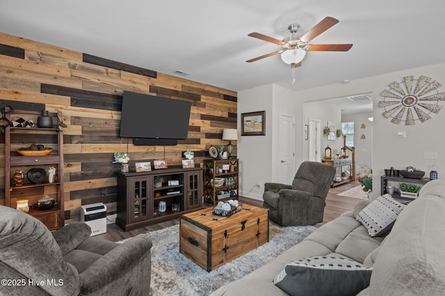 living room featuring hardwood / wood-style flooring, ceiling fan, and wood walls