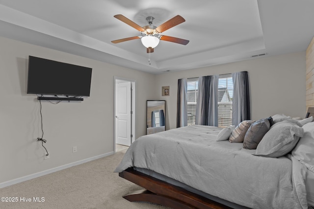 carpeted bedroom featuring ceiling fan and a raised ceiling