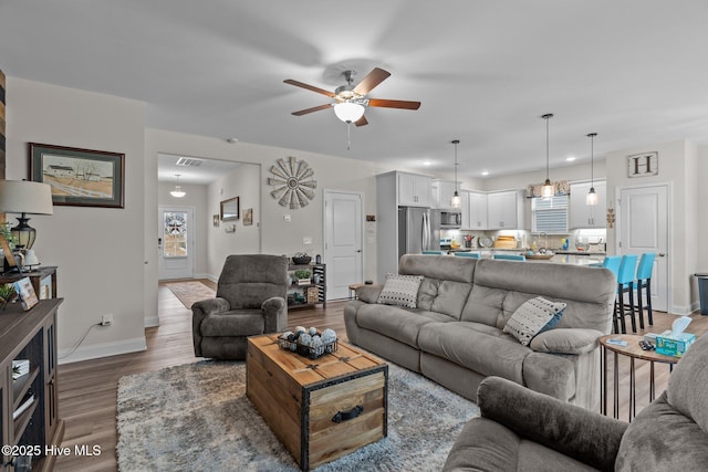 living room featuring ceiling fan and dark hardwood / wood-style flooring