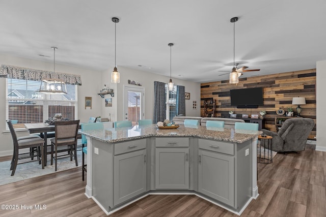 kitchen with pendant lighting, hardwood / wood-style floors, a kitchen island, and wood walls