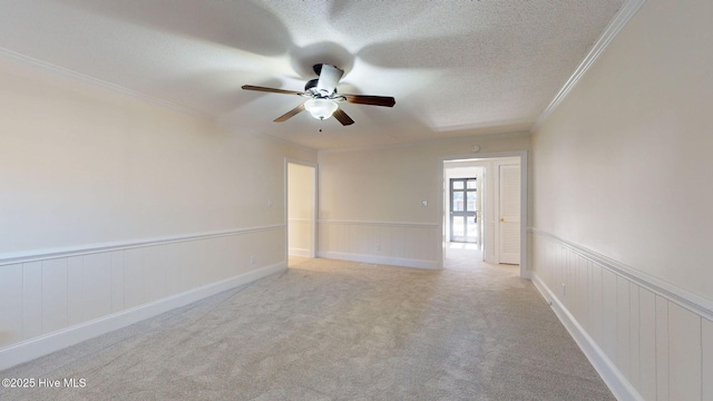 spare room with ornamental molding, light carpet, ceiling fan, and a textured ceiling