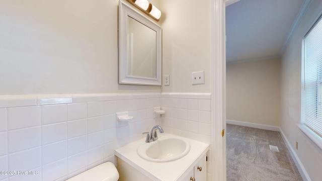 bathroom featuring vanity, ornamental molding, toilet, and tile walls