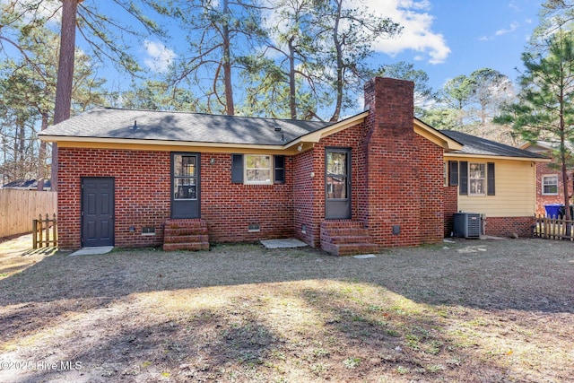 rear view of house featuring central AC and a lawn